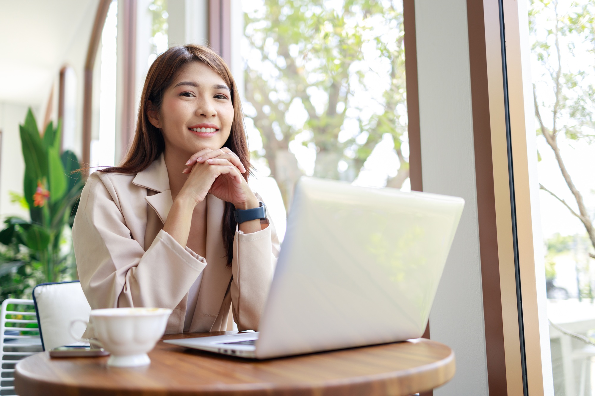 Asian woman smiling and working by laptop in the coffee shop. Business concept.