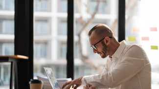 Businessman using laptop computer in office. Happy middle aged man, entrepreneur, small business