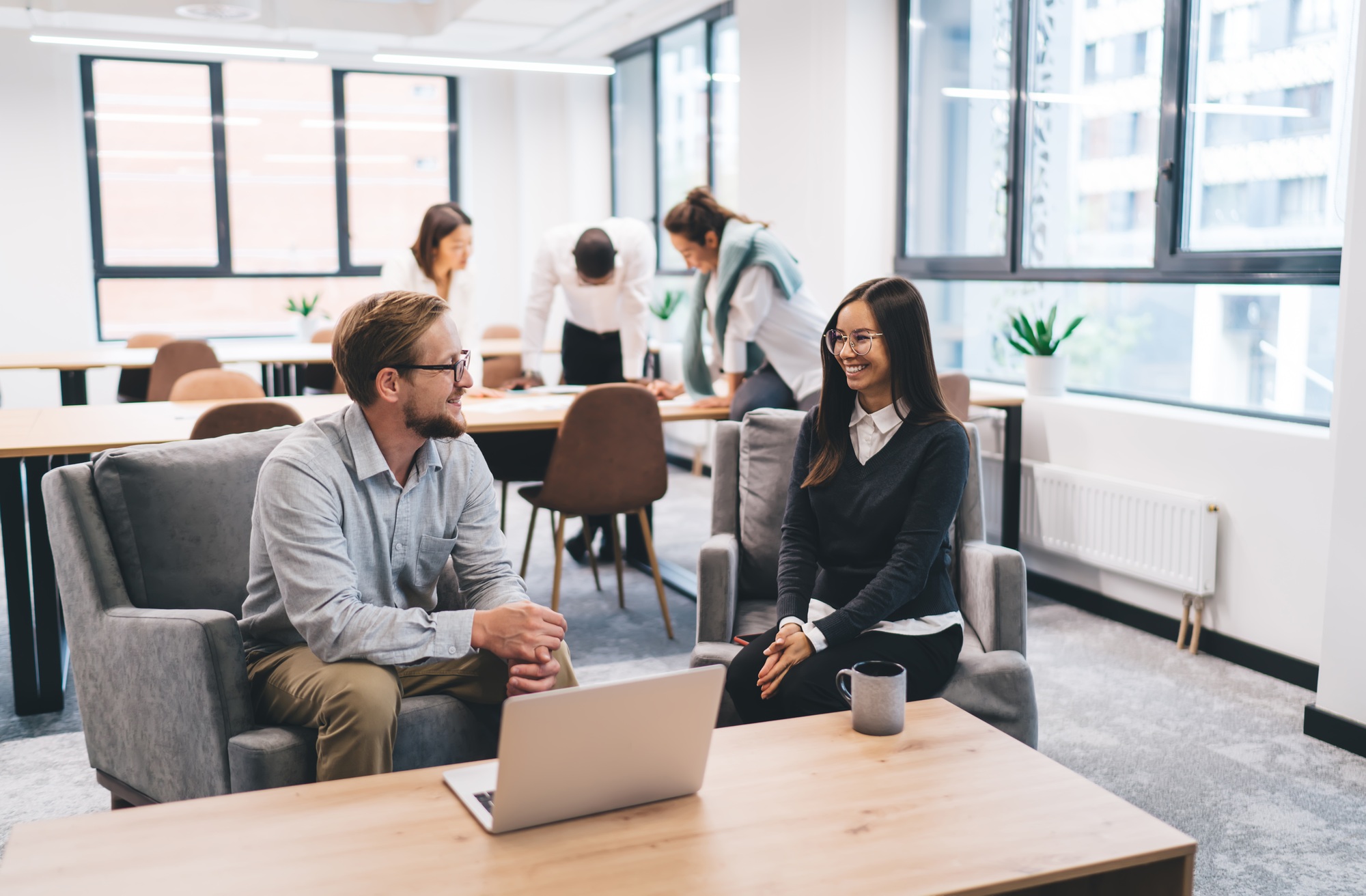 Cheerful colleagues discussing business ideas at table in office