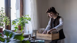 Creative hipster girl wearing beret organizing art tools and painting materials