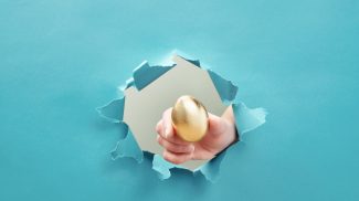 Hand gives golden egg through paper hole. Concept of profitable offer