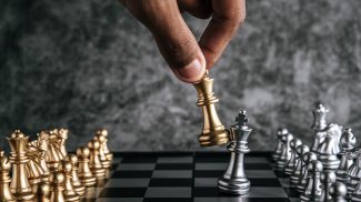 Hand of man playing chess for business planning and comparison of metaphor, selective focus