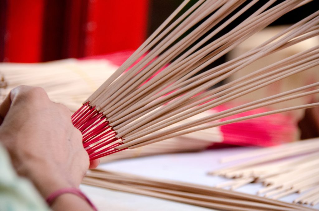 Hands holding and arranging incense sticks with red bases