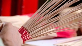 Hands holding and arranging incense sticks with red bases