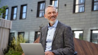 Ideas for business. Portrait of cheerful elegant middle aged businessman smiling while working on