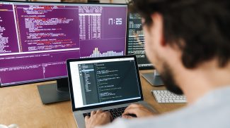 Image of focused caucasian programmer man working with computers