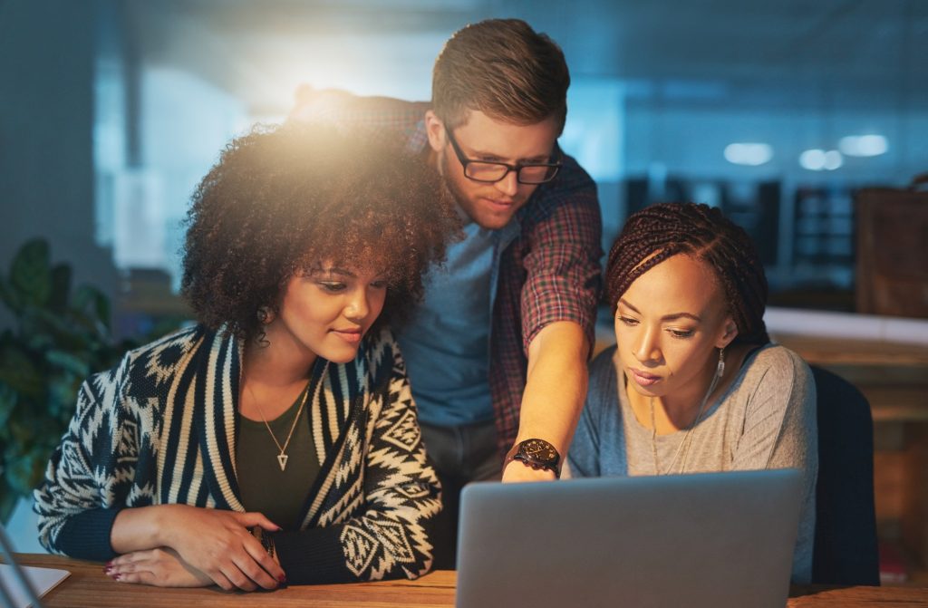 Making a few final changes. Cropped shot of a group of young people working late in the office.