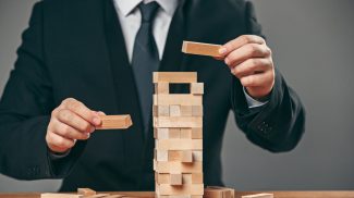 Man and wooden cubes on table. Management concept