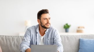 Millennial freelancer working on laptop and looking aside, thinking about successful business