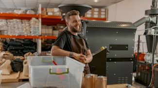 Portrait of smiling business owner on background of own small coffee factory looking away
