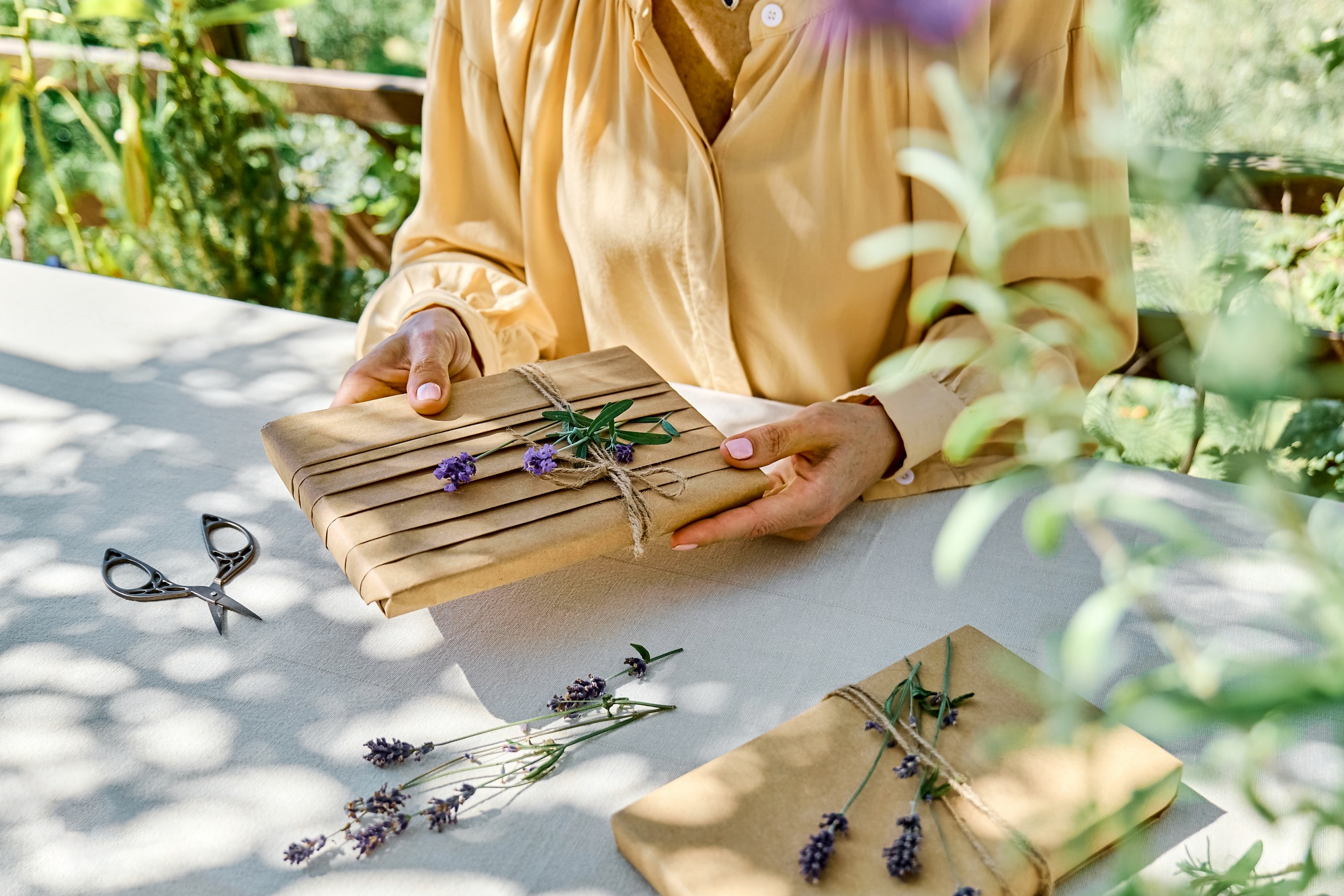 Woman making hand made gift package with craft recycled paper and dried lavender flowers