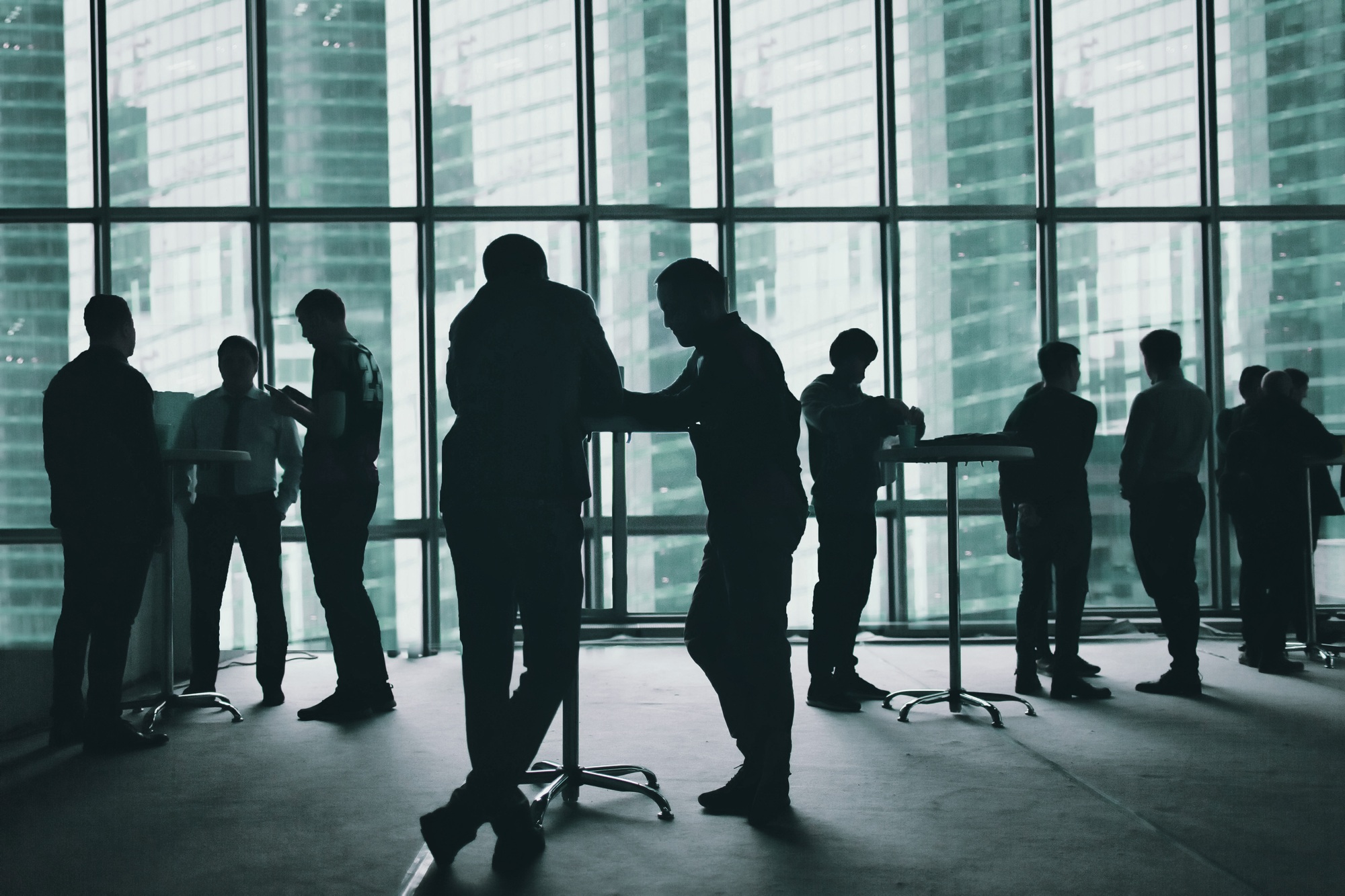 Several silhouettes of business people interacting business big window background. Faces changed.