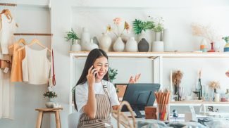 Small business owner talking on the phone with customers in a small shop.