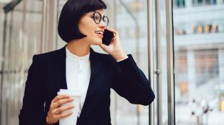 Successful businesswoman talking on smartphone on street