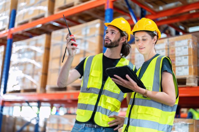 Warehouse worker standing check stock quantity of product and key information to tablet pc