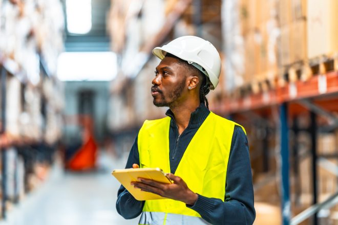 Warehouse worker taking inventory with digital tablet in logistic warehouse