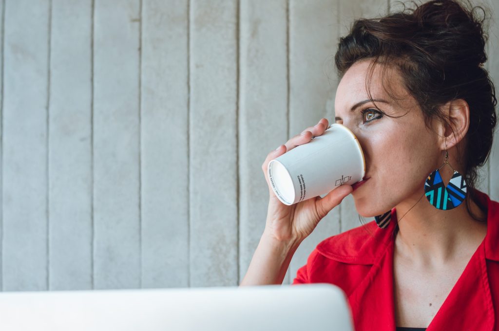 young caucasian woman drinks coffee while thinking about marketing strategies for her business