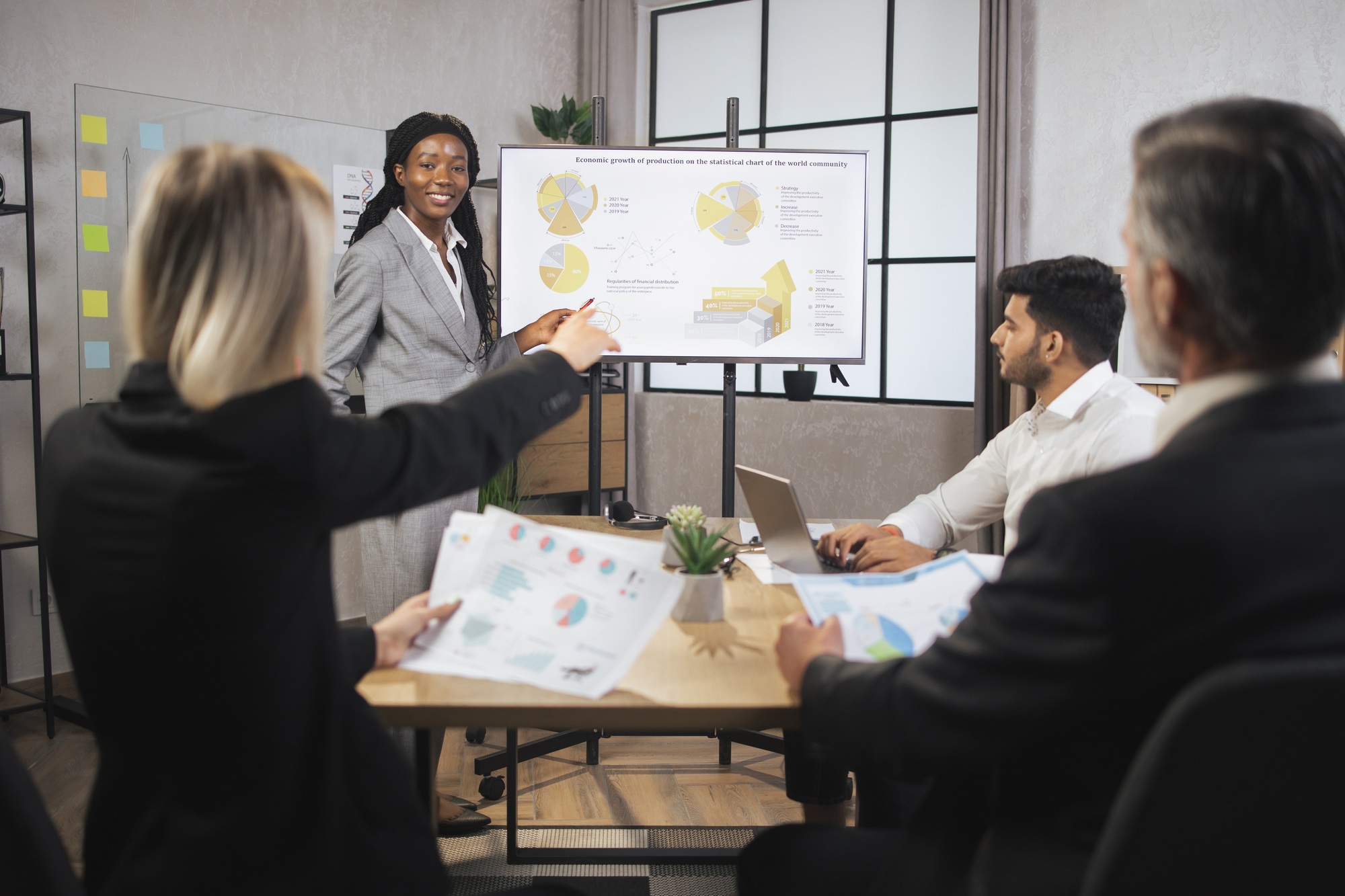 Young confident african business lady, showing company's work infographics on digital wall screen