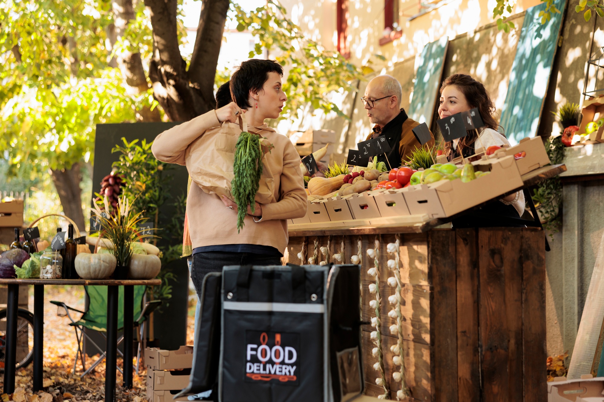 Young delivery woman with thermal bag picking up order at local marketplace