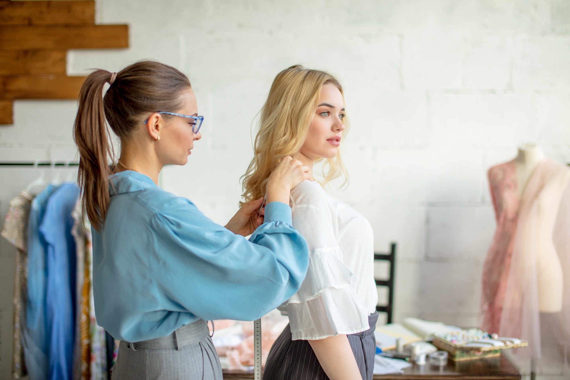 Young fashion designer taking measurements of a woman to design new dress.